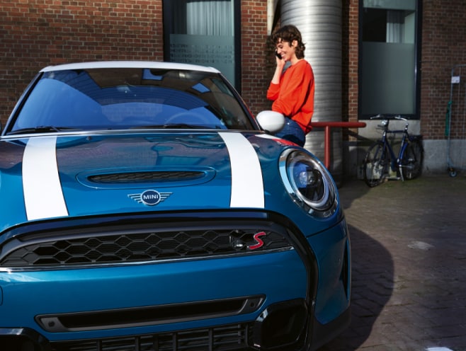 A woman smiles down at a MINI.